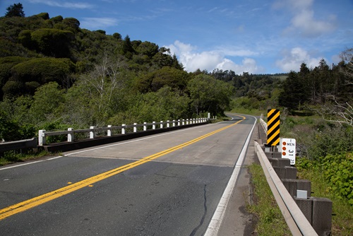 Current photo of the Elk Creek Bridge located on State Route 1 in Mendocino County. The bridge is a two-lane road with narrow shoulders and wooden railings. A sign indicates mile marker 31.35.