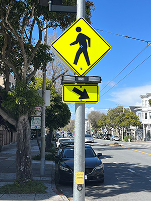 A pedestrian crossing sign with a rectangular rapidly flashing beacon beneath the sign.
